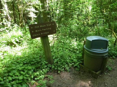 Trash can along the Old Main Trail with wayfinding sign
